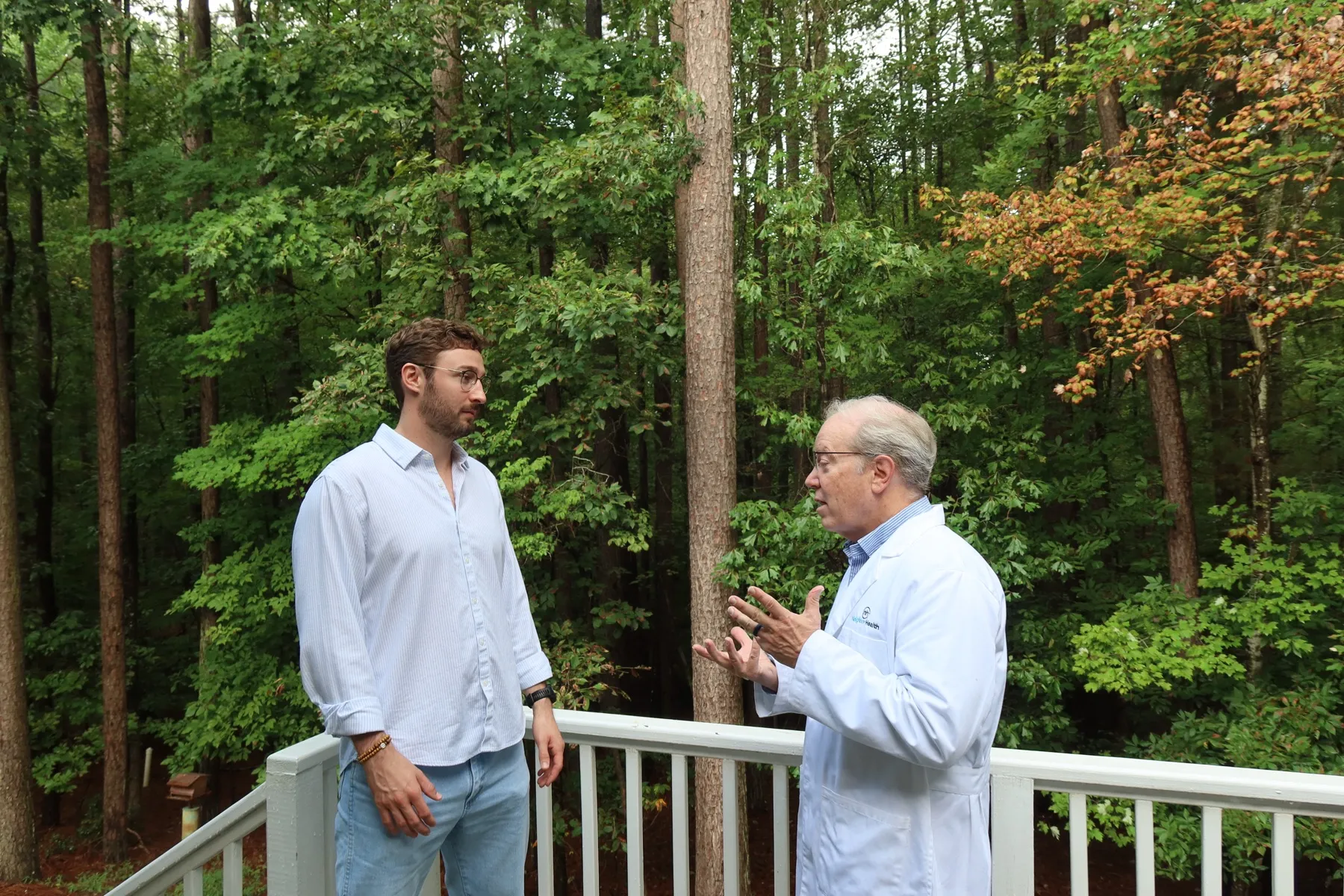 Dr. Briggs talking with a younger man on a wooded deck