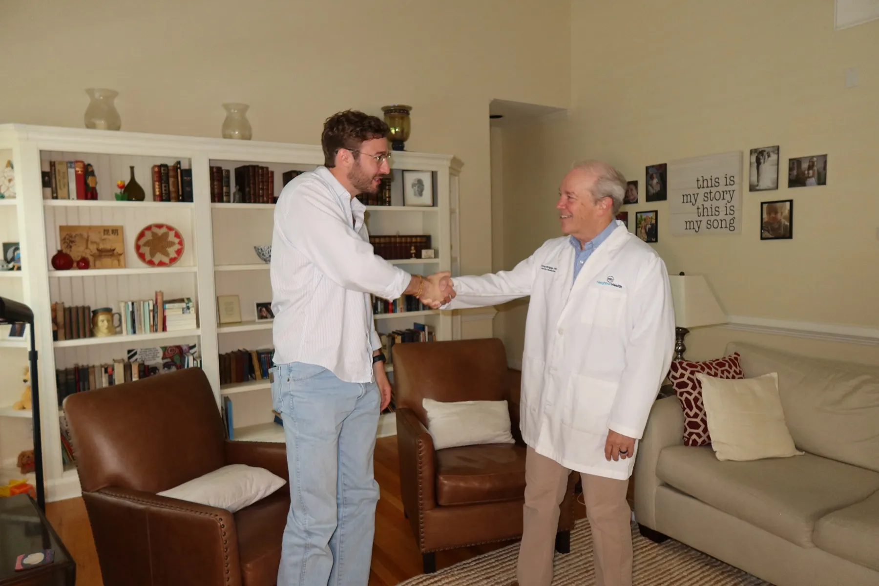 Dr. Briggs greeting a patient with a handshake in a warm living-room setting